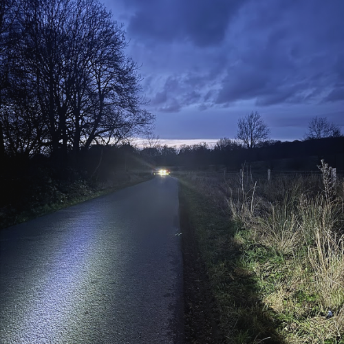 Five Gates Lane near Belton at dusk with headlights approaching along the rural road